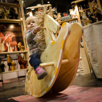 Kind spielt auf einem handgefertigten Schaukelpferd aus Fichtenholz, Erzgebirge traditionelles Spielzeug.